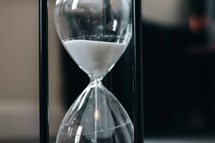 Sanduhr mit weißem Sand in einem schwarzen Gestell