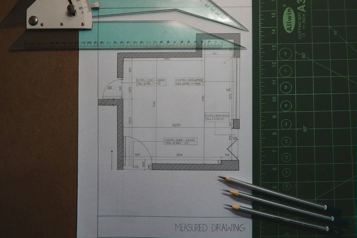 Bemaßte Aufmaßzeichnung eines Raums mit Lineal, Winkelmesser und Bleistiften, von oben fotografiert