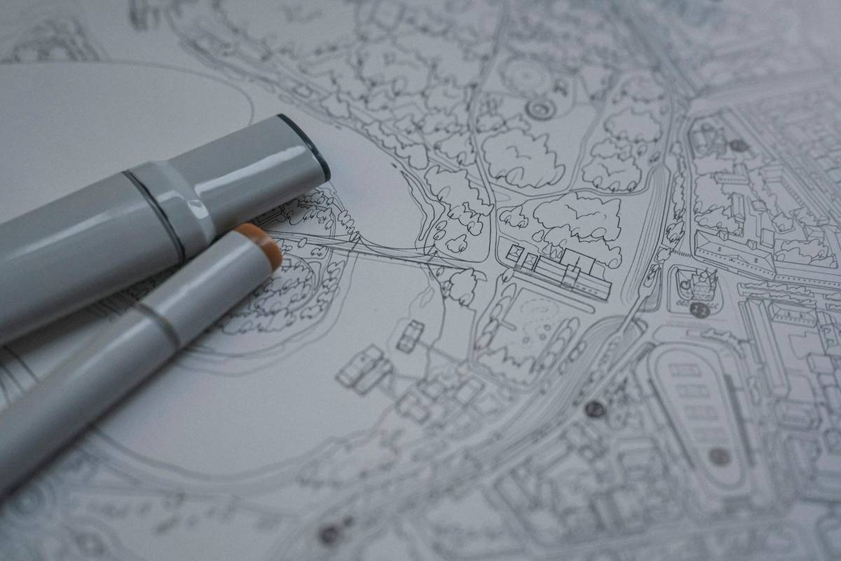 Zwei graue Marker auf einem gezeichneten Stadtplan mit Gebäuden und Grünflächen